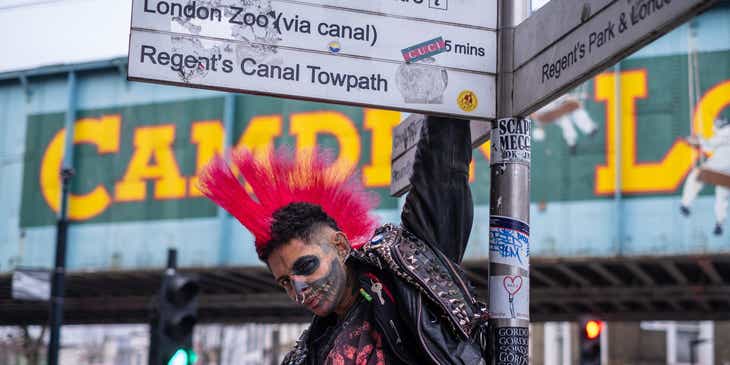 Une personne au style punk accrochée à un panneau de signalisation dans le quartier de Camden Town à Londres..