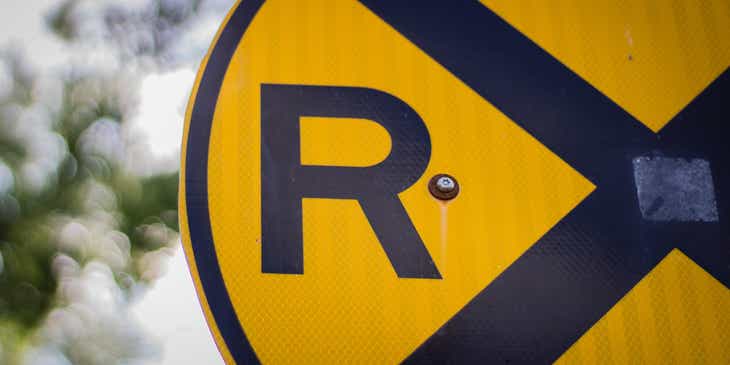 Zbliżenie na literę „R” umieszczoną na żółto-czarnym znaku drogowym.