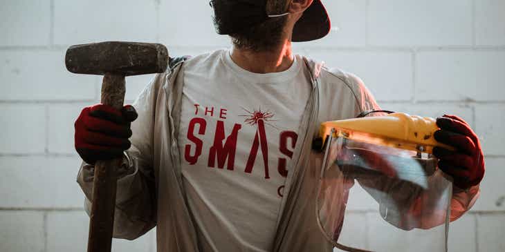 Un hombre que sostiene un mazo y equipo de protección en un logo de sala de ira.