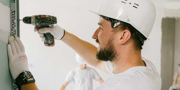 Een lachende werknemer die renovaties uitvoert in het huis van een klant.
