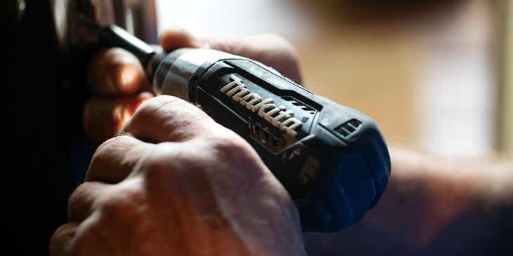 A man repairing a door with a power drill.