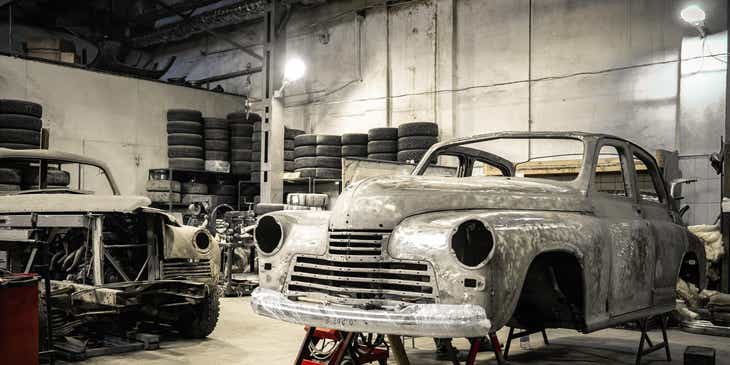 La carrosserie d'une vieille voiture sur des vérins dans une entreprise de restauration de voitures.