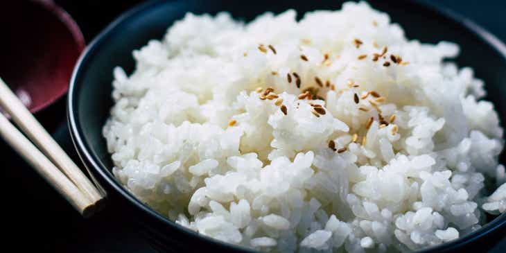 Un bol de riz cuit garni de graines de sésame noir.