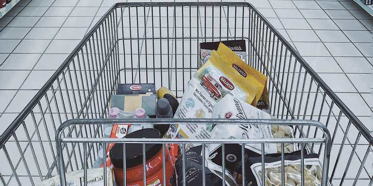 Un carrello con dei prodotti nella corsia di un supermercato.