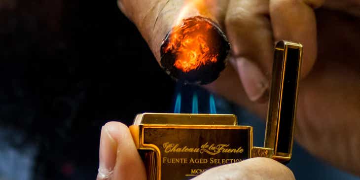 Ein Mann zündet mit einem goldenen Feuerzeug in einem Tabakladen eine Zigarre an.