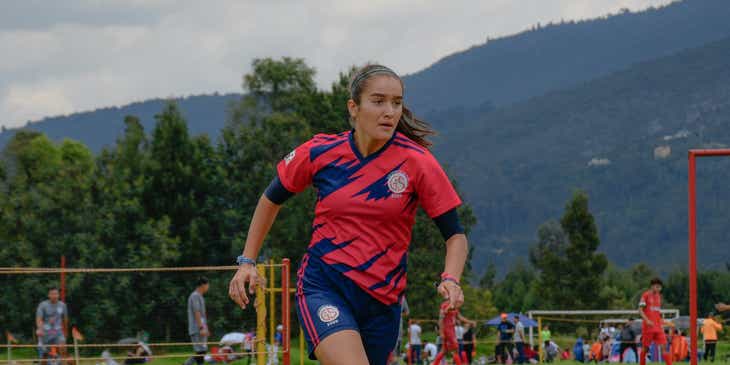 Seorang wanita bermain sedang bermain pertandingan soccer yang kompetitif.