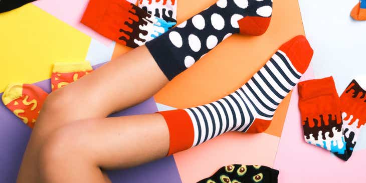 Kobiece nogi w różnokolorowych skarpetkach na barwnym tle.