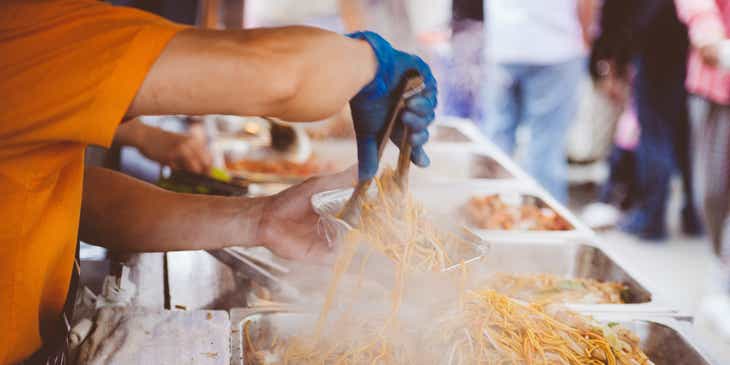 A person preparing a parcel of street food.