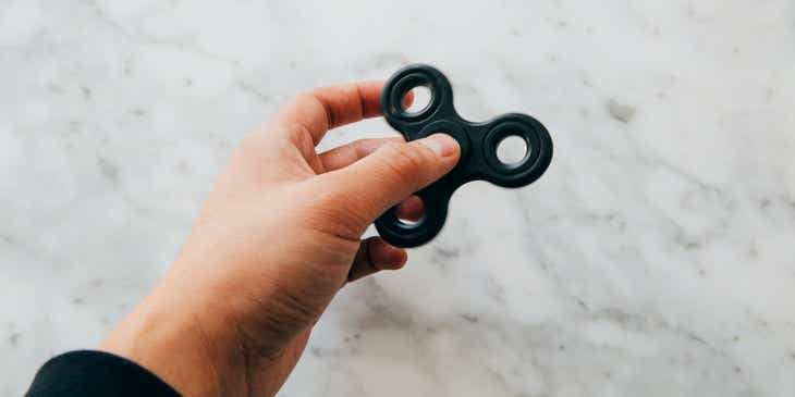 A person holding up a black fidget toy.