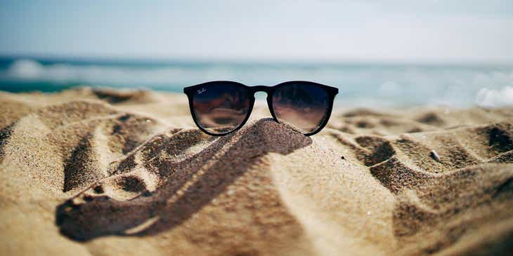 Bir sahildeki kumun üzerinde duran bir güneş gözlüğü.