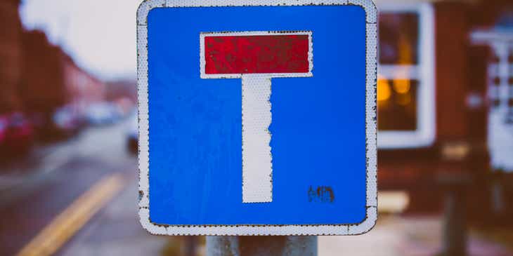 Rambu jalan berwarna biru, putih, dan merah yang menampilkan huruf T.