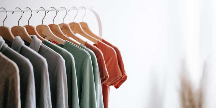 Berbagai variasi kaos digantung di rak pakaian.