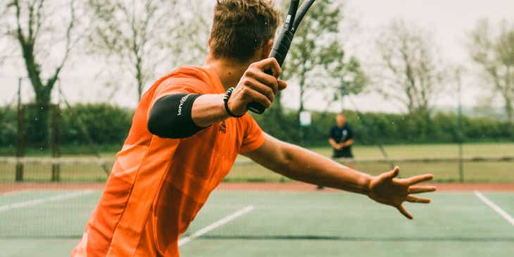 Seorang pria bermain tenis dengan temannya.