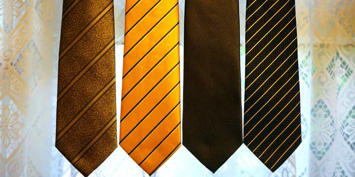 Cuatro corbatas de varios colores perfectamente alineadas sobre un fondo gris claro en un logo con corbatas.