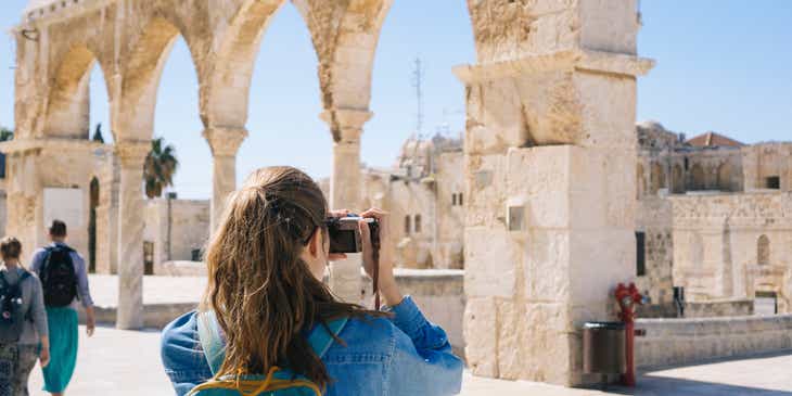 Une femme prend des photos sur un site touristique qui comprend des ruines anciennes.