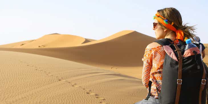 A traveler exploring a desert on camelback.