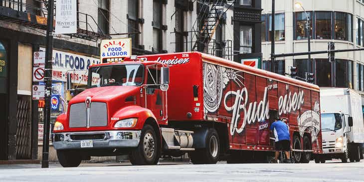 Ein roter LKW einer Speditionsfirma mit einer großen Budweiser-Werbung