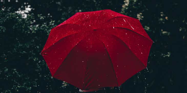 Una persona con un ombrello rosso sotto la pioggia.