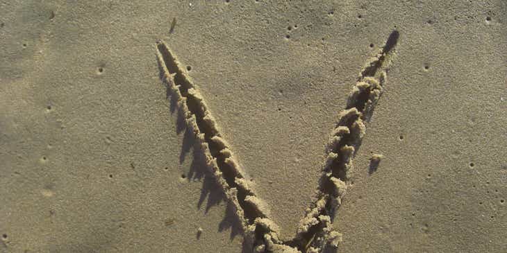 Huruf V yang digambar di pasir pantai.