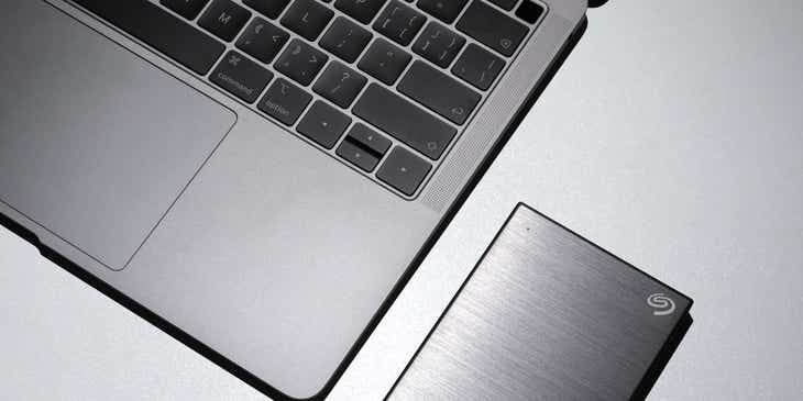 Een laptop op een witte tafel en een externe harde schijf die wordt gebruikt voor dataherstel.