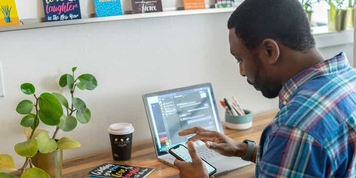 Seorang virtual assistant yang sedang bekerja menggunakan laptop dan handphone di rumahnya.