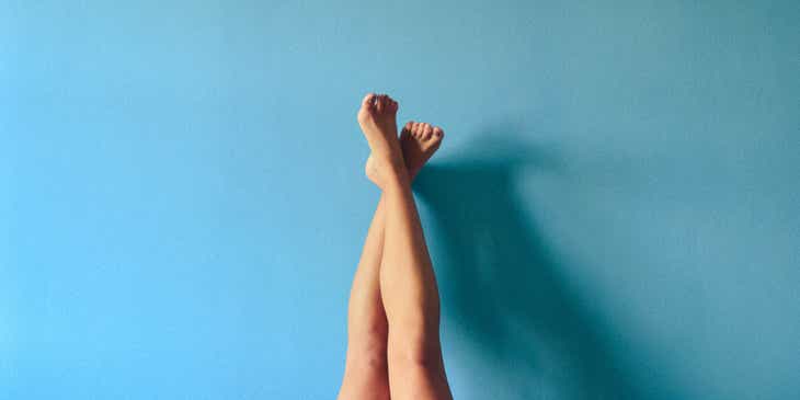 Mavi bir duvara yaslanmış yeni ağda yapılmış bacaklar.