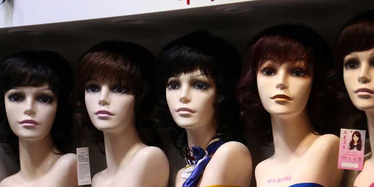 A row of mannequin busts on display wearing wigs.