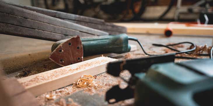 Narzędzia używane do obróbki drewna otoczone wiórkami drewna, ułożone na stole w warsztacie cieśli.