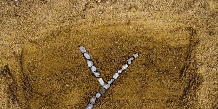 Kerikil-kerikil yang membentuk huruf Y di atas pasir.