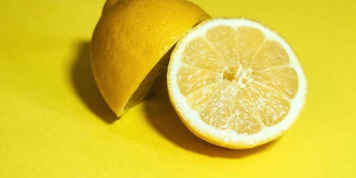 Eine halbierte Zitrone liegt auf einer gelben Oberfläche.