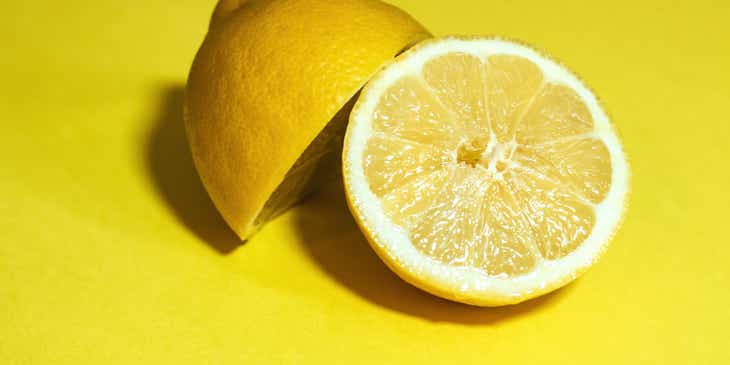 Sebuah lemon yang dibelah dua pada permukaan berwarna kuning.