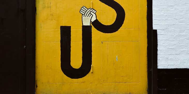 Ein Straßenkünstler hat ein gelbes Quadrat mit den schwarzen Buchstaben „S“ und „U“ auf eine Mauer gemalt.