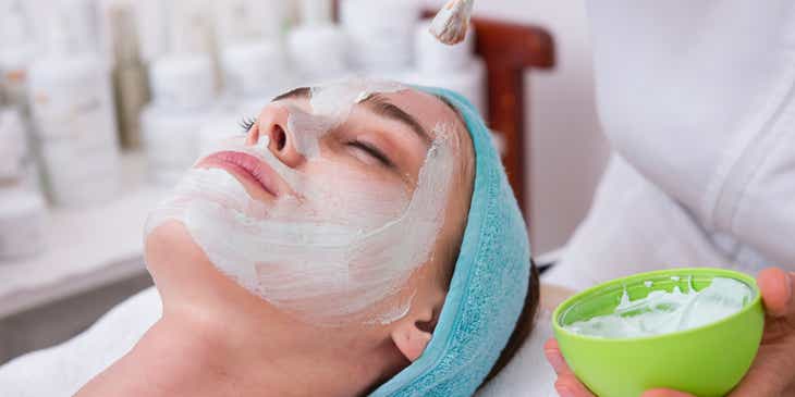 Yüz bakımı işlemi sırasında yüzüne maska uygulanan bir kadın.